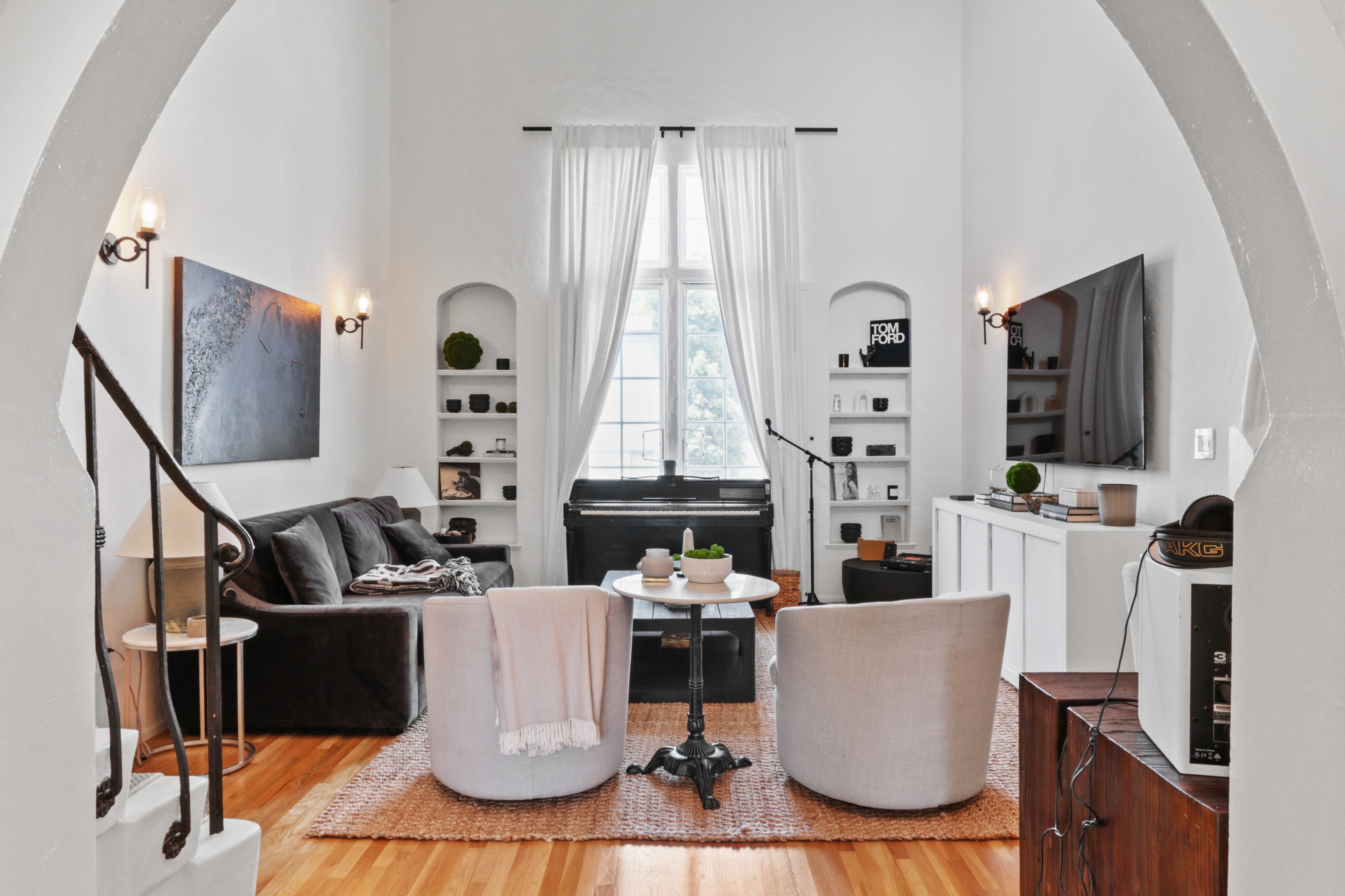 Living room with dramatic arched entry, built-in shelving and piano