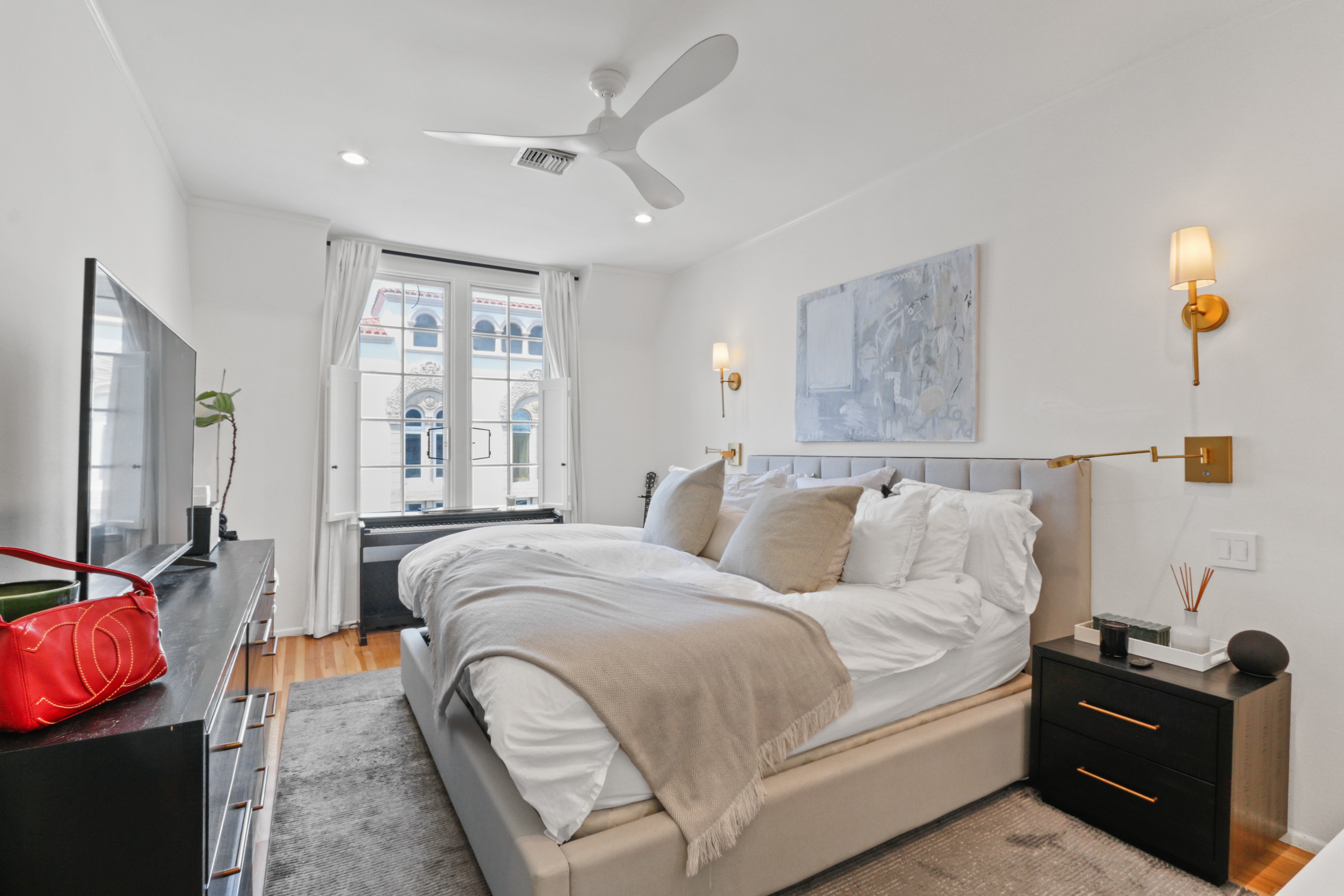 Bright master bedroom with gold sconces and oversized windows