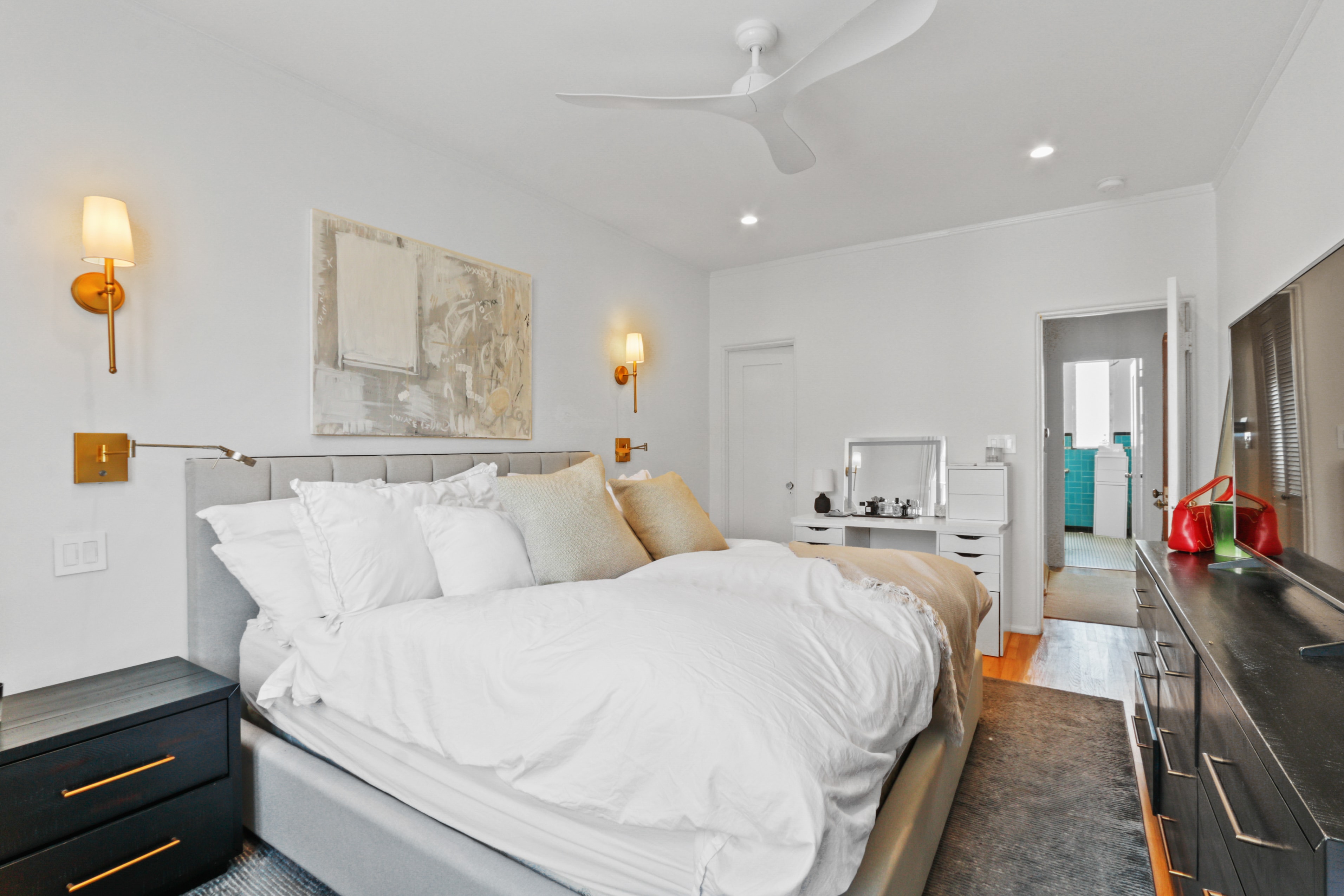 Bedroom with gold sconces, ceiling fan and en-suite bathroom