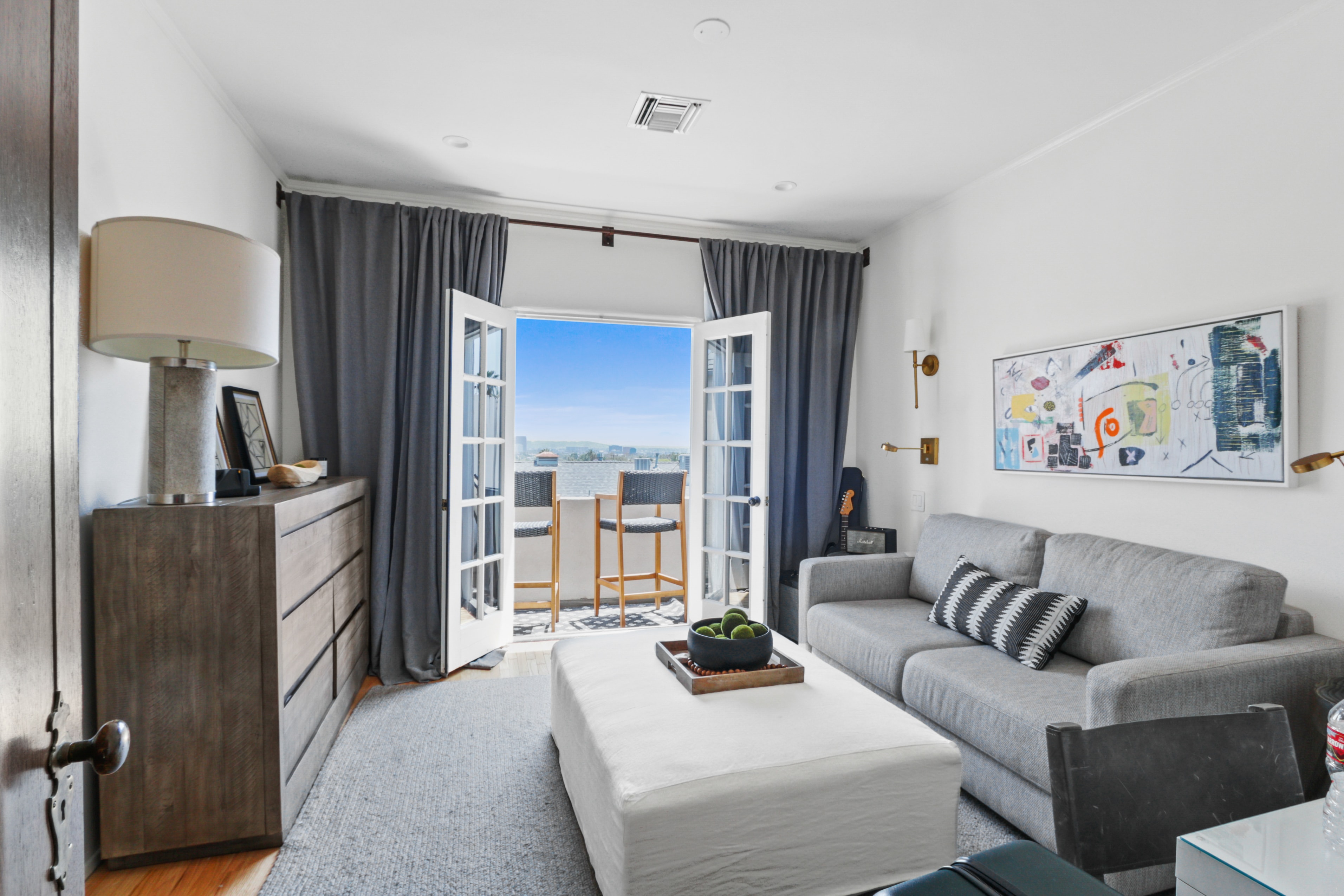 Bright living room with French doors opening to a city view balcony
